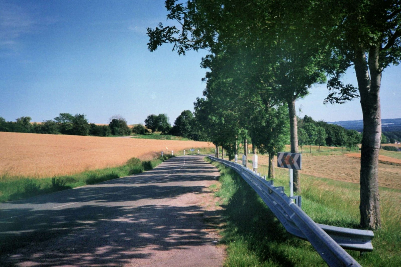 a country road with a fence and a field in the background